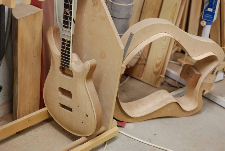 The electric guitar in this picture is one of the first Sander ever made, with a pearl inlay of a vulture on a tree. (De Gier means vulture.) It was never finished though, the neck was glued at the wrong angle…